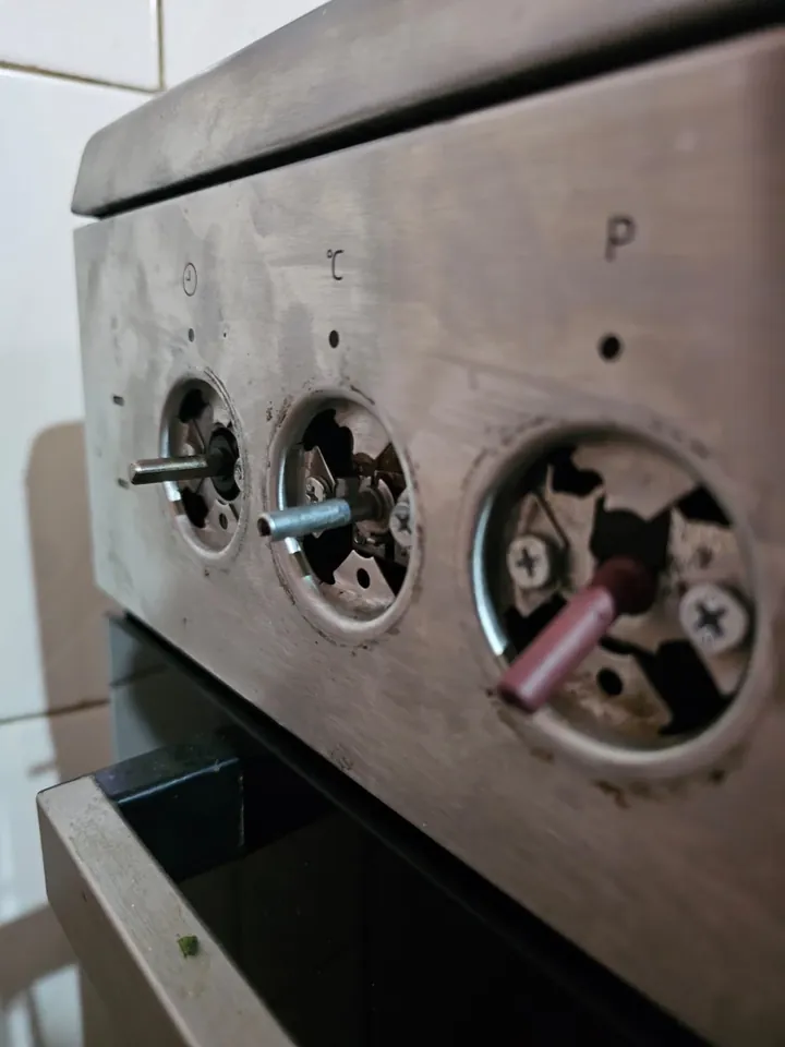 Cooker with the knobs removed to reach the gas valves