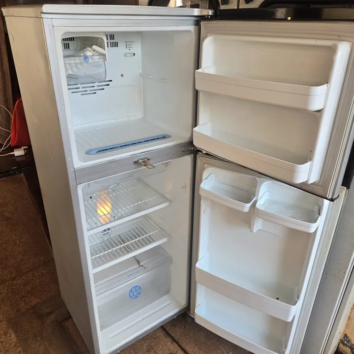 White double-door fridge opened during a repair visit