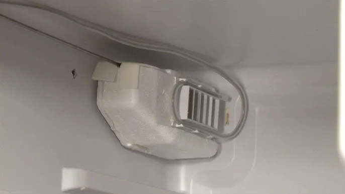 Close-up of the thermostat and light housing inside a fridge