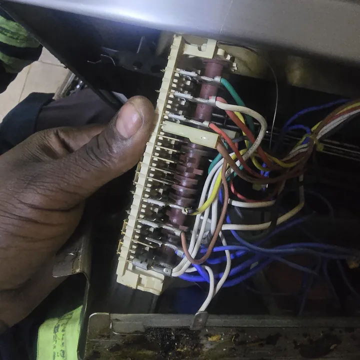 Technician checking the wiring terminals behind an oven